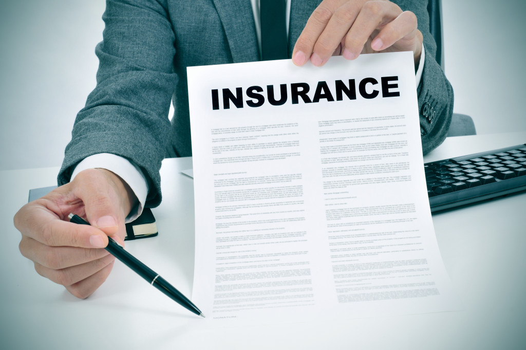 A man in suit showing an insurance document in his office