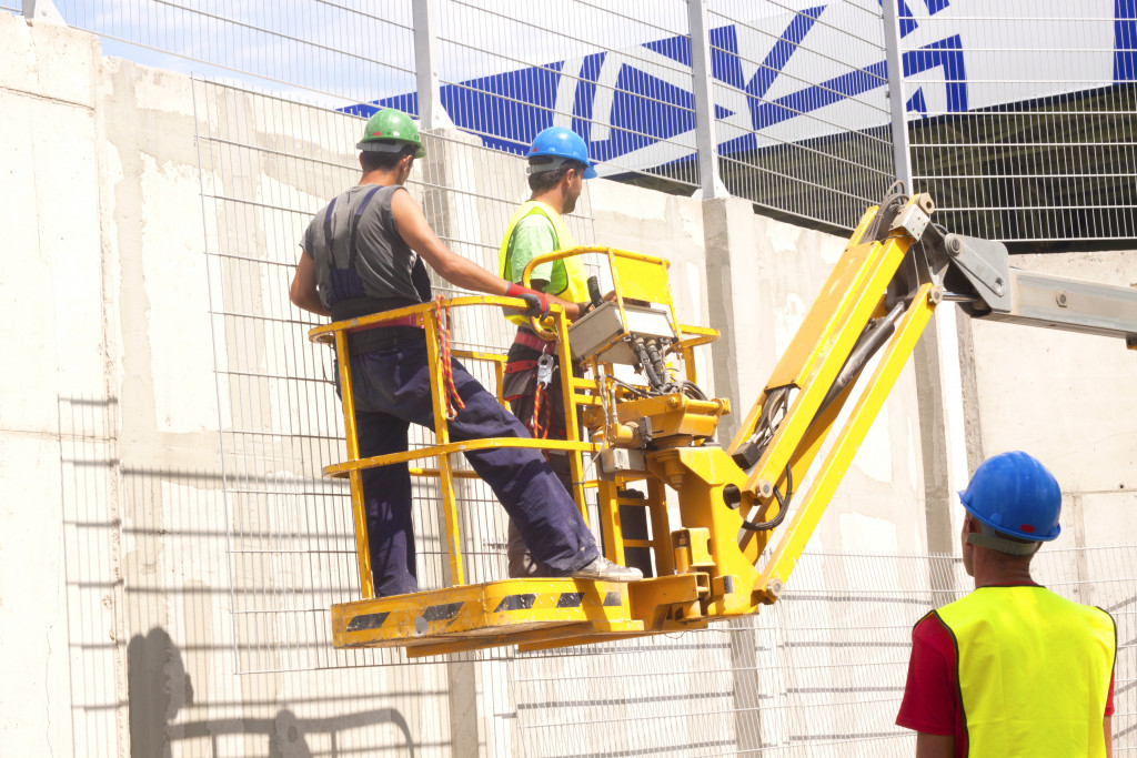 Construction workers elevated using a hydraulic mobile construction platform.