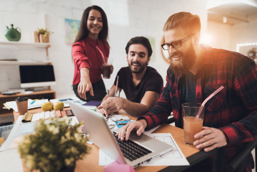 Two male and one female co workers working together shows a good office environment 