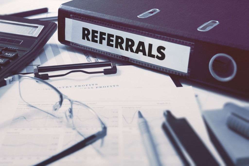 Referrals - Ring Binder on Office Desktop with Office Supplies. Business Concept on Blurred Background. Toned Illustration.