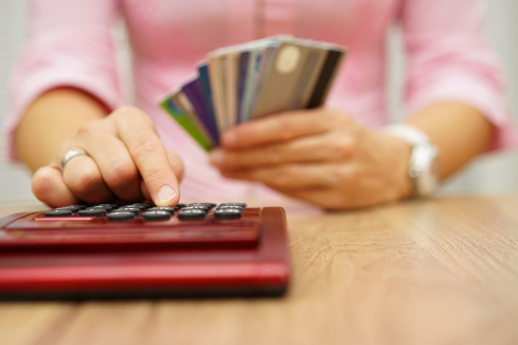 woman holding credit cards computing bills